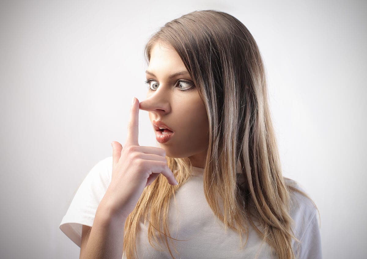 Woman looks surprised as she touches growing nose