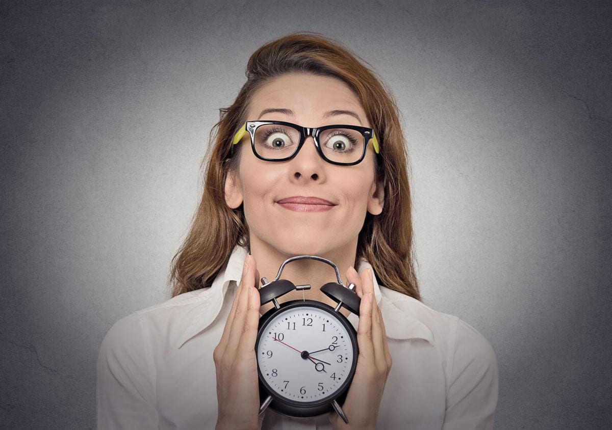 A girl wearing glasses holds a clock in her hands