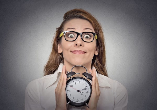 A girl wearing glasses holds a clock in her hands