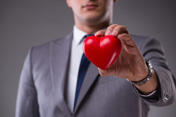 Corporate man in suit holds a heart in his hand.
