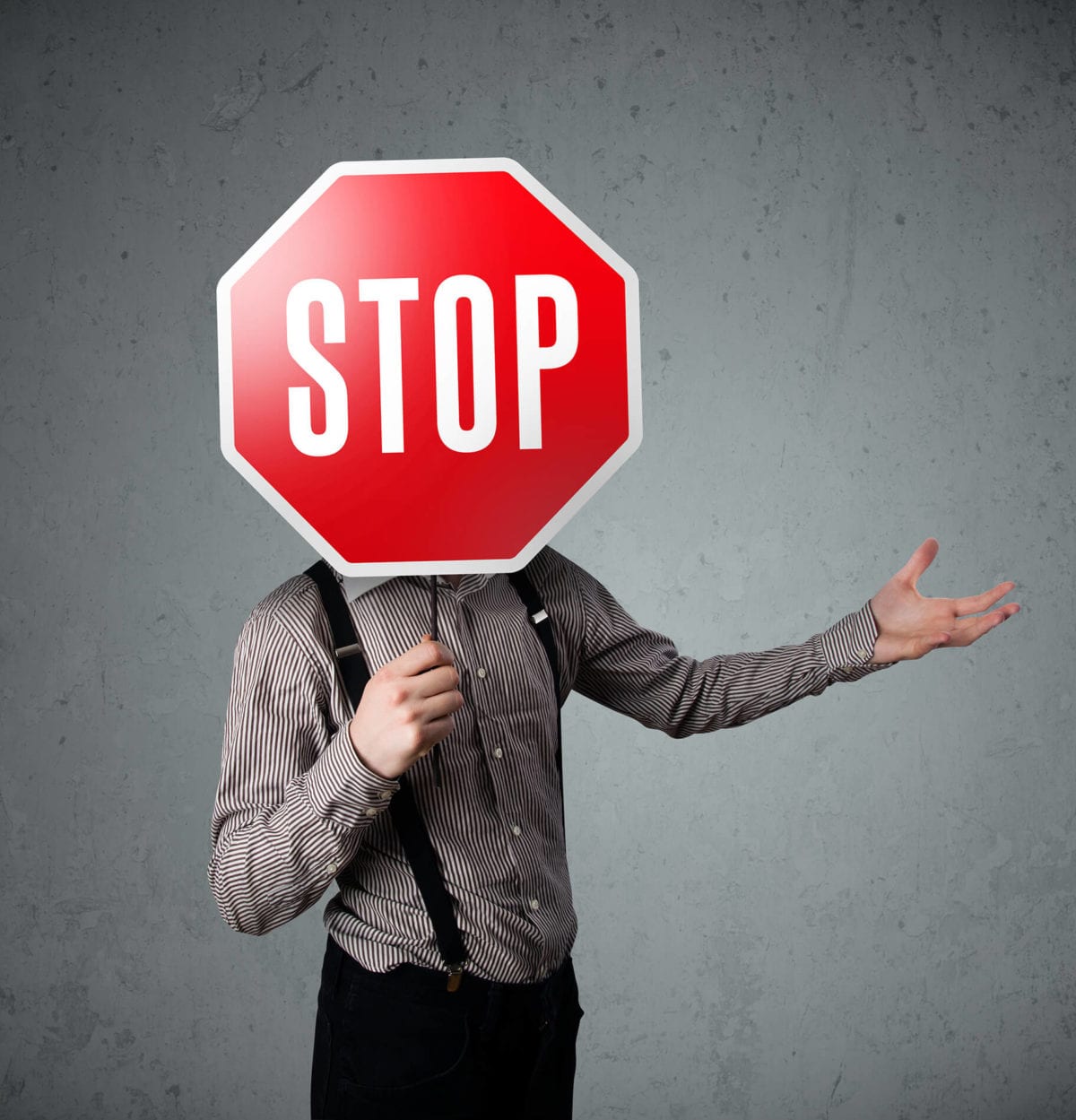 A man holds a stop sign in front of his face