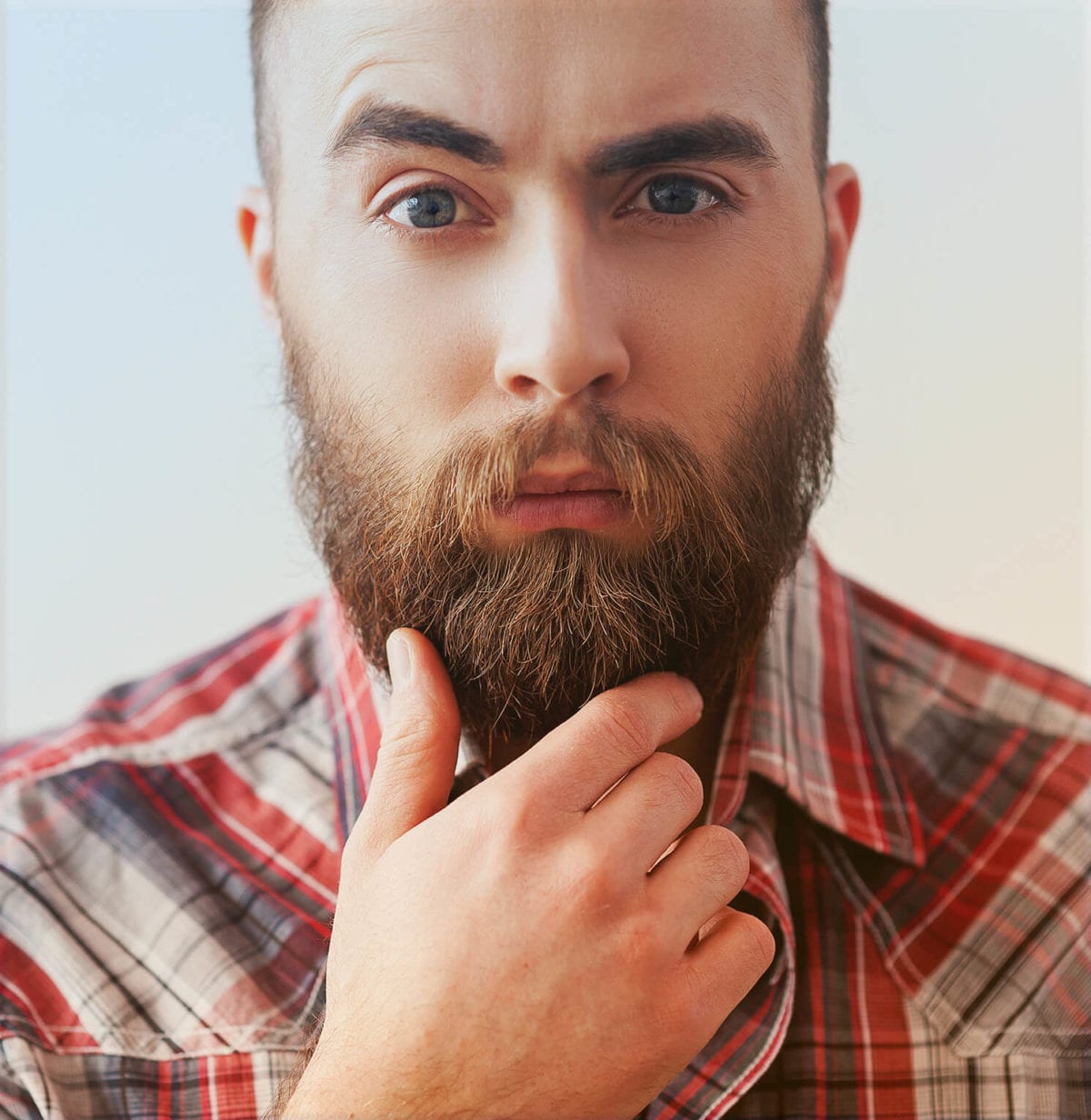 A young man strokes his beard