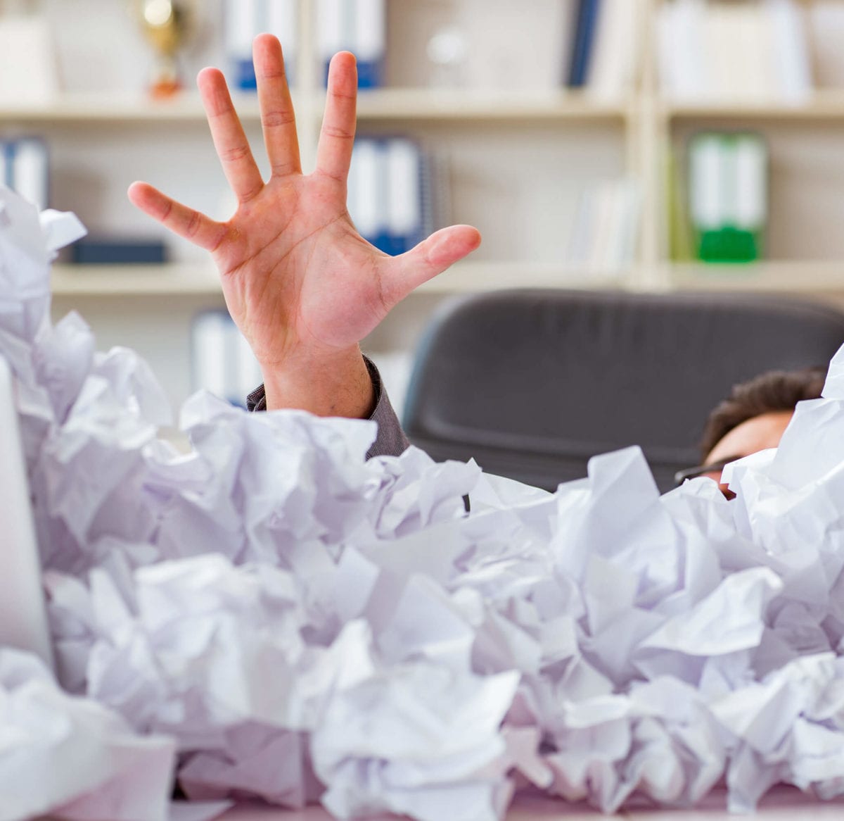 A hand rising from a pile of crumpled papers