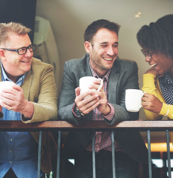 Colleagues laugh together over a cup of coffee