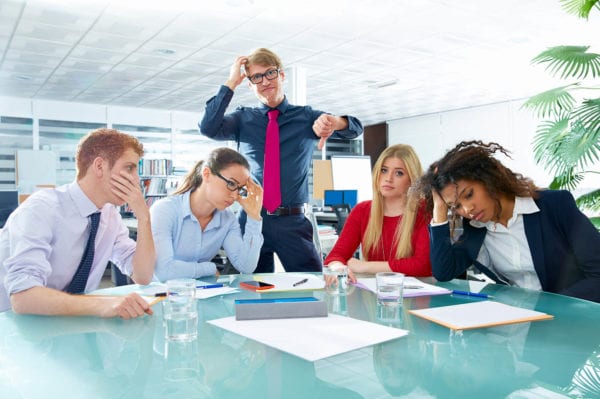 Disgruntled employees sit around a conference table