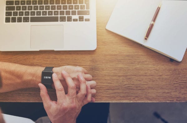 Business man checks time on smart watch at home office